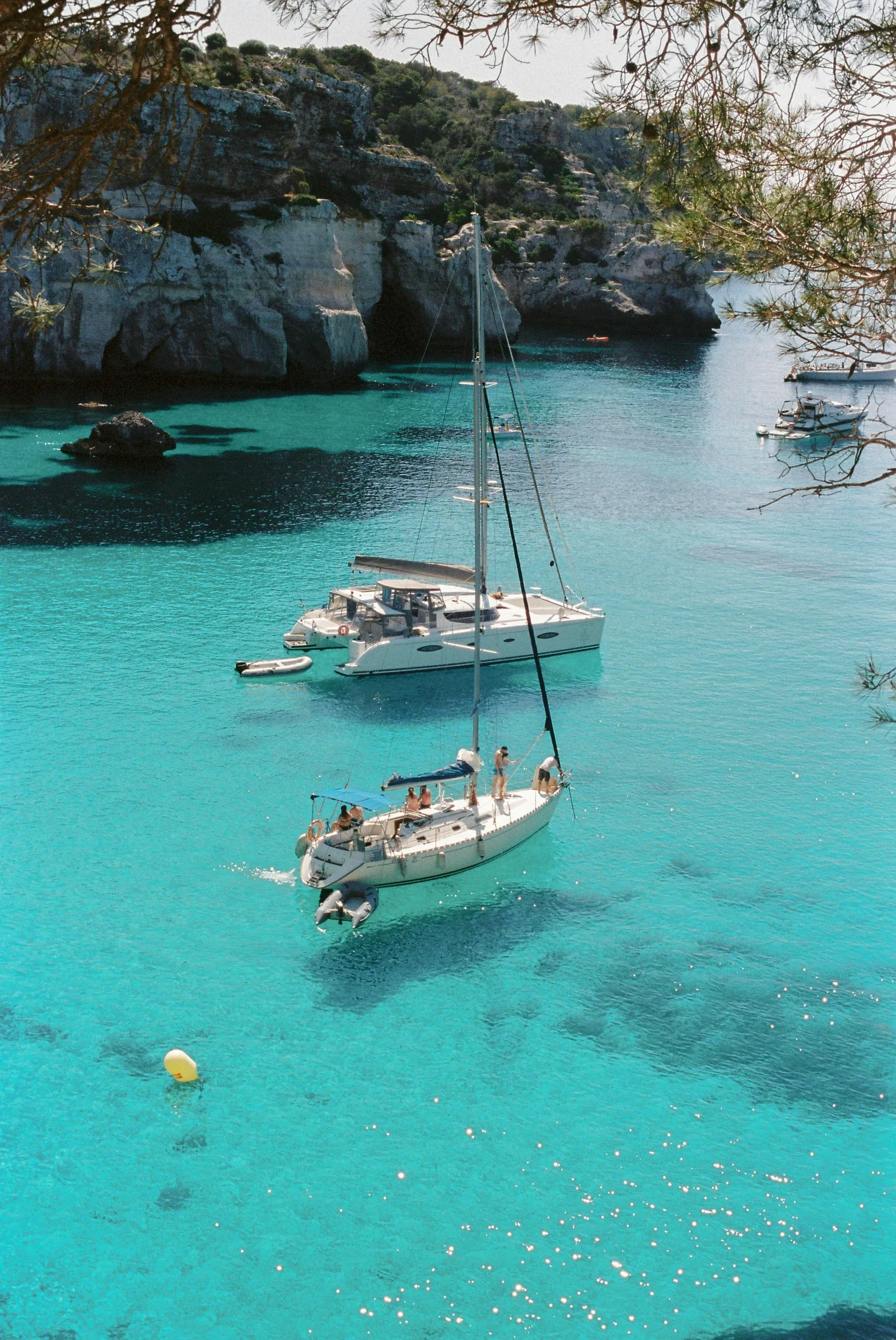Velero en una cala de aguas turquesas en Menorca, una imagen de vida tranquila.