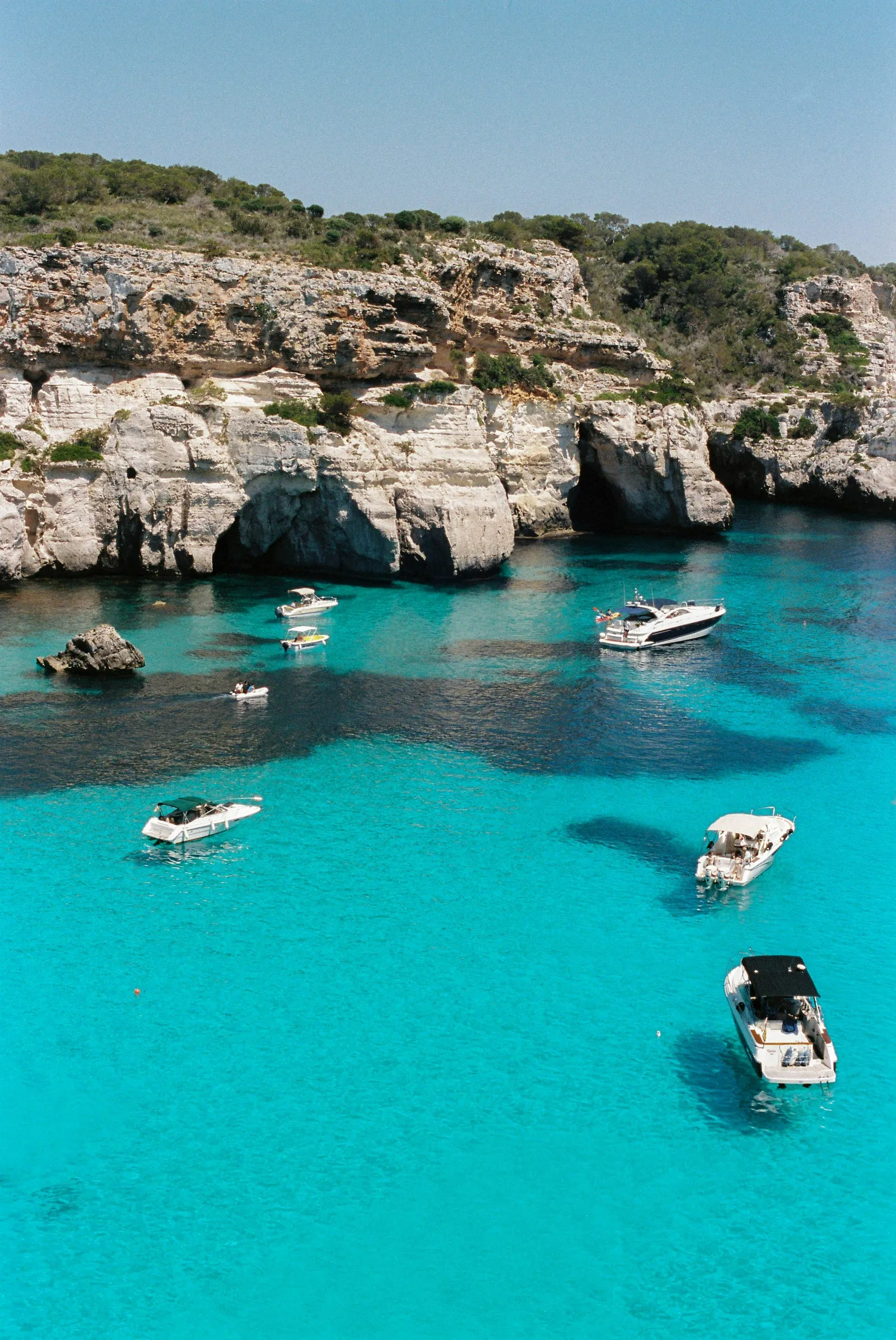 Turquoise water and boats in a Menorca cove.